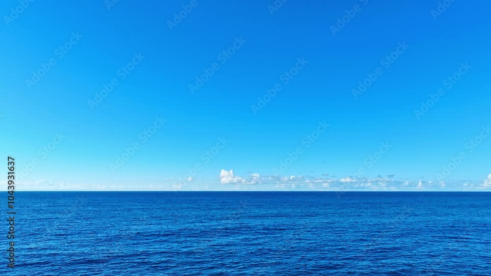 Summer background of blue surface of Caribbean sea. Sunny clear sky and deep blue ocean. Exotic water landscape with clouds on horizon. Travel to tropical island. Tranquility of ocean nature. Summer background of blue surface of Caribbean sea. Sunny clear sky and deep blue ocean. Exotic water landscape with clouds on horizon. Travel to tropical island. Tranquility of ocean nature.
