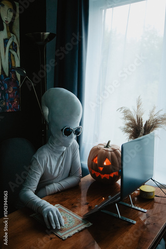 Wallpaper Mural Teenager in Halloween full-body freaky white costume with carved pumpkin laptop on table studying online Torontodigital.ca