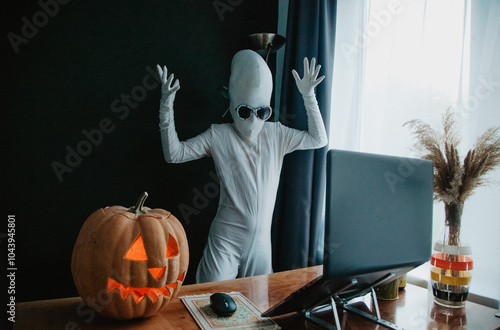 Wallpaper Mural Teenager in Halloween full-body freaky white costume with carved pumpkin laptop on table studying online Torontodigital.ca