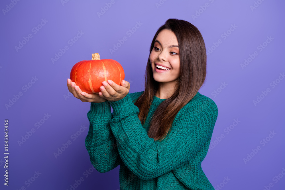 Portrait of nice young girl look hands hold pumpkin wear sweater isolated on violet color background Portrait of nice young girl look hands hold pumpkin wear sweater isolated on violet color background