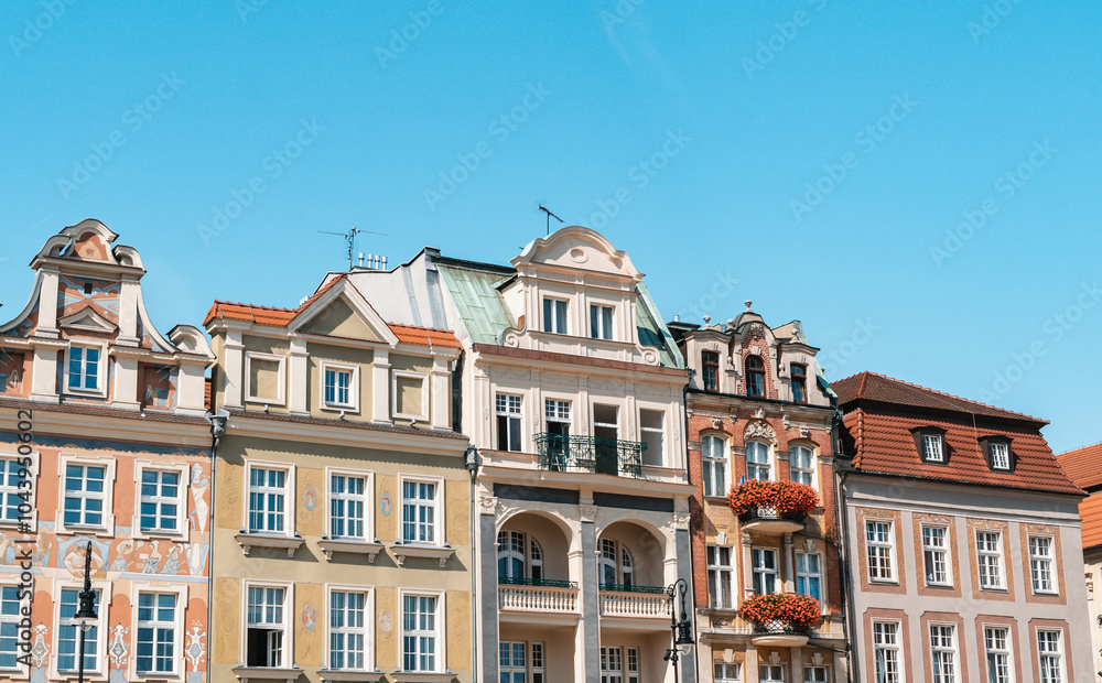 Fototapeta premium Colorful Historic Buildings and Houses on Stary Rynek Square in Poznań, Poland, with a Blue Sky and Mural Art