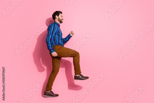 Full length photo of positive funny man wear stylish clothes step empty space isolated on pink color background photo