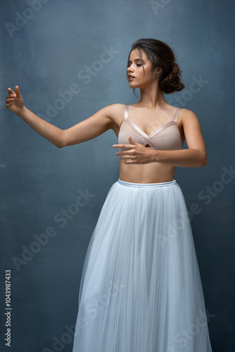 Woman, ballet and dancer with performance in studio on tutu skirt for for rehearsal on gray background. Female person, gen z and serious or confident as artist for practice, audition and competition photo