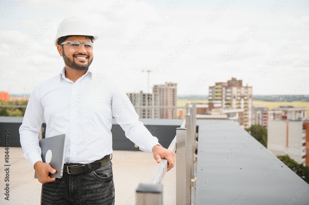Indian male engineer wearing helmet at construction site. Copy space. Real estate Indian male engineer wearing helmet at construction site. Copy space. Real estate