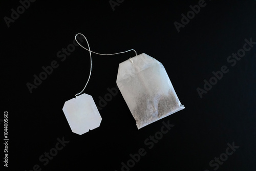 single tea bag flat overhead on black background angled