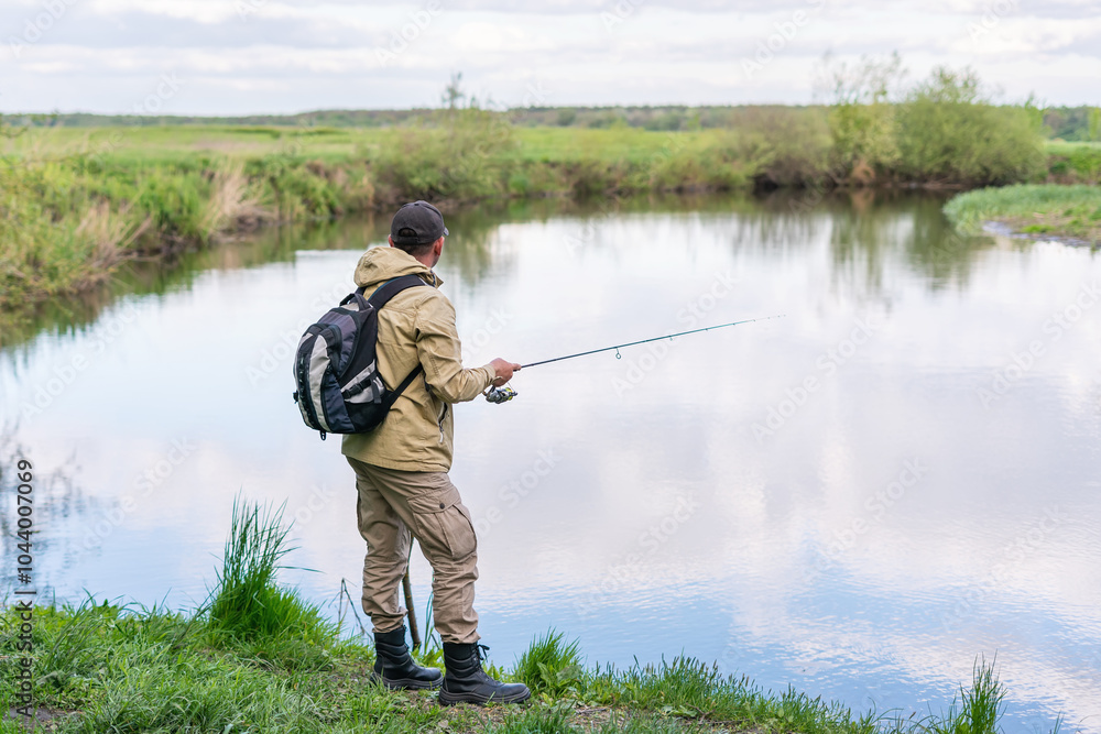 A man catches fish with a spinning rod on the river bank A man catches fish with a spinning rod on the river bank