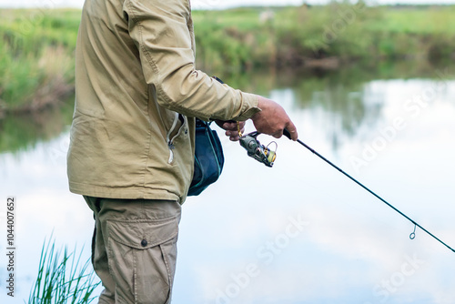 Foto A man catches fish with a spinning rod on the river bank