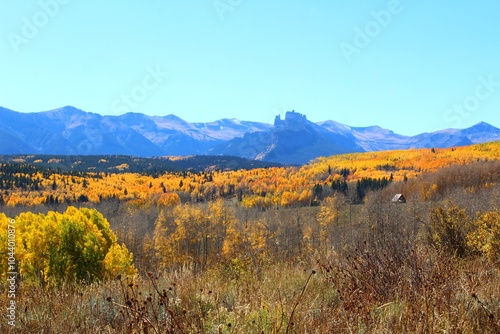 autumn landscape in the mountains with cabin and yellow aspen groves 