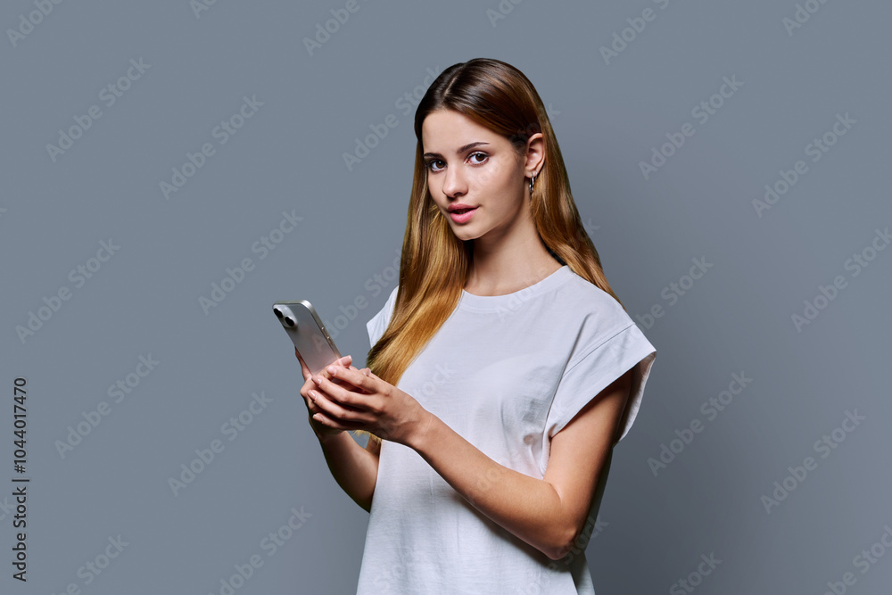 Young beautiful woman using smartphone on grey studio background Young beautiful woman using smartphone on grey studio background
