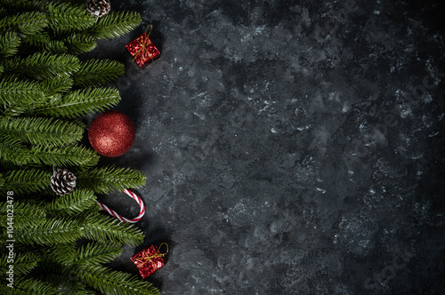 Christmas border with fir tree branches and red balls isolated on black background with empty space for greeting text photo