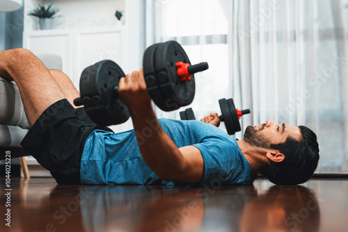 Athletic body and active sporty man lifting dumbbell weight for effective targeting muscle gain at gaiety home as concept of healthy fit body home workout lifestyle. photo