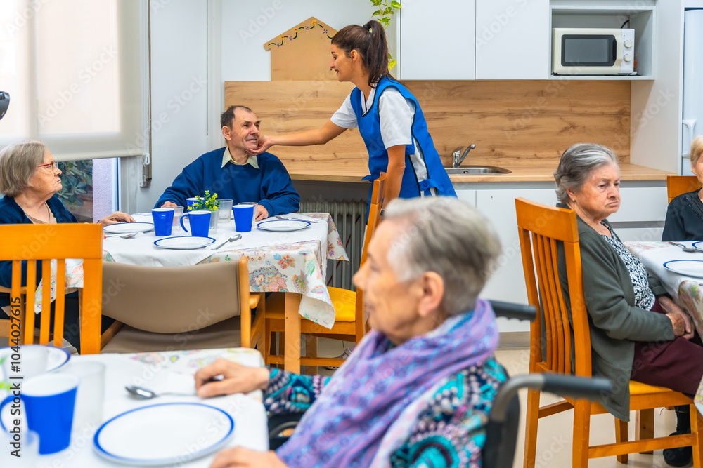 Obraz premium Nurse talking with senior people while eating at geriatrics
