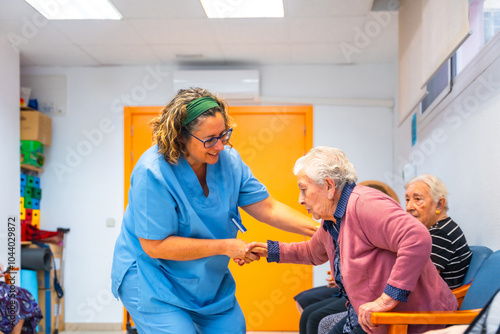 Fotografie Nurse helping to stand up to senior woman at geriatrics