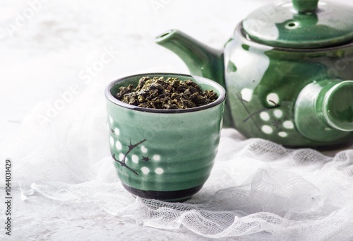 Green and white ceramic teapot and mug filled with herbal infused drink photo