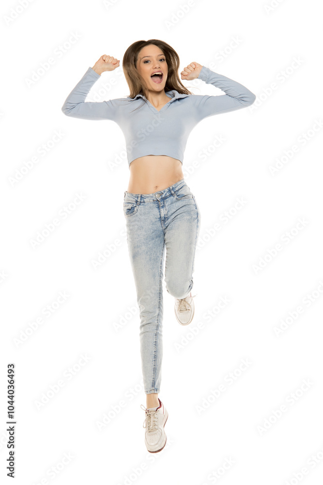 Beautiful young happy woman in a blue jeans and shirt jumping on a ...