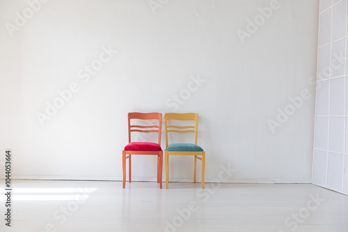 two vintage chairs in the interior of an empty white room with a window photo