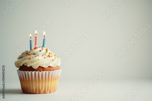 A single cupcake with three lit candles on top.