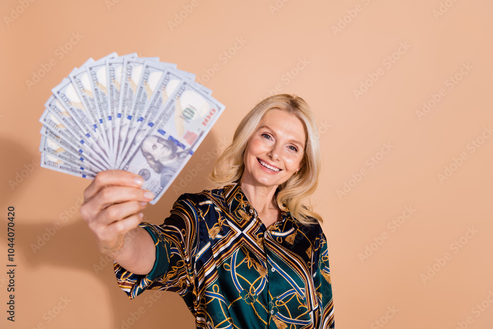 Photo portrait of senior successful business lady holding much money year profit deal showing you motivation isolated on beige color background Photo portrait of senior successful business lady holding much money year profit deal showing you motivation isolated on beige color background