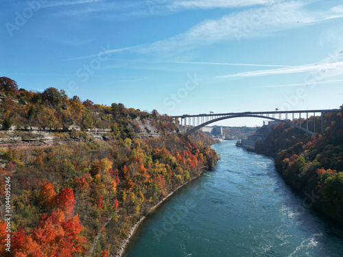 Aerial over the Niagara River and gorge from the international border crossing Queenston-Lewiston bridge between New York, United States and Ontario, Canada towards Niagara Falls during autumn.