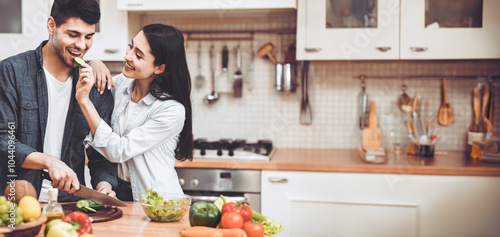 Wallpaper Mural Having Fun. Young lady feeding her handsome boyfriend, cooking salad together at kitchen, empty space Torontodigital.ca