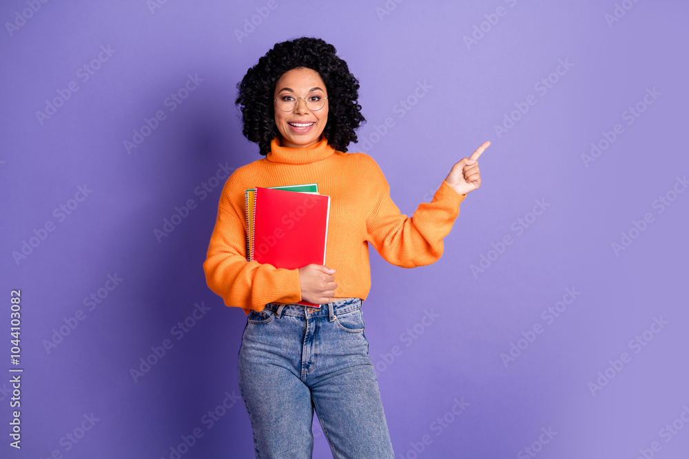 Photo of shiny attractive lady dressed knitted pullover holding book showing finger empty space isolated purple color background Photo of shiny attractive lady dressed knitted pullover holding book showing finger empty space isolated purple color background