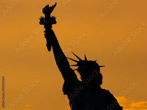 Stunning silhouette of the upper Statue of Liberty suring sunset in New York Harbor, within New York City. NY, USA