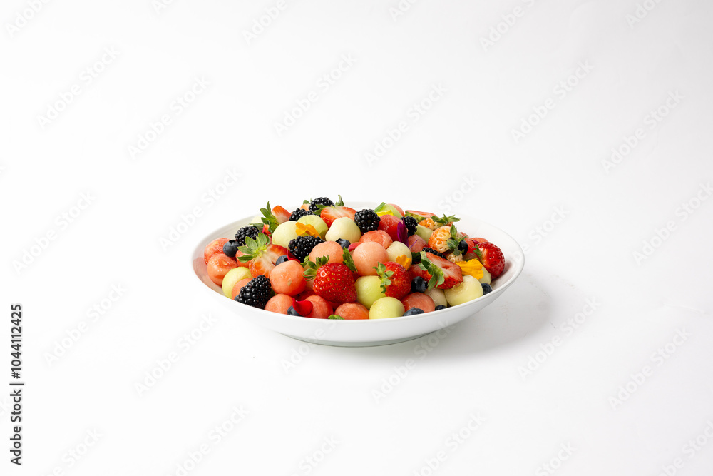 Seasonal fruit salad cut and placed in a lrge white serving bowl. Seasonal fruit salad cut and placed in a lrge white serving bowl.