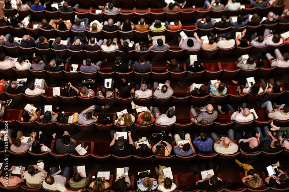 Theater audience with a view from above with almost all the seats occupied, arranged in rows. Theater audience with a view from above with almost all the seats occupied, arranged in rows.