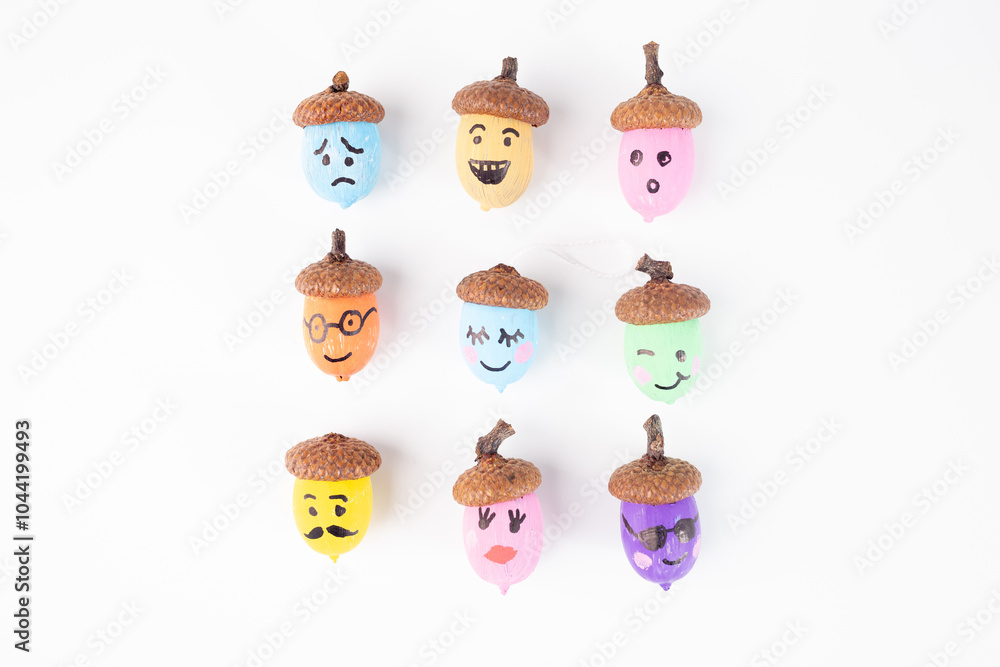Fototapeta premium Colorful hand painted acorns collection with various facial expressions on a white. craft projects and autumn decorations. DIY and creativity concept,