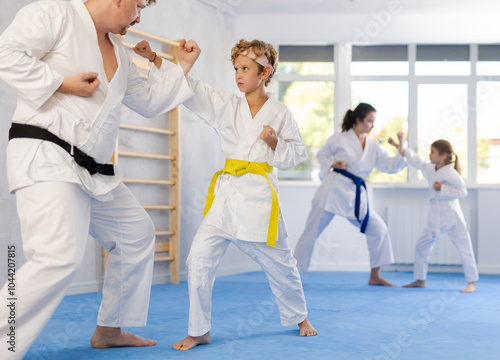 Schilderij op canvas Father and son karatekas in kimonos practice karate fighting in studio