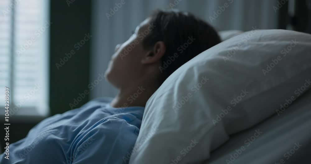 A young girl in a hospital room, lying on a bed, looking out the window, turns around and looks at the camera . A young girl in a hospital room, lying on a bed, looking out the window, turns around and looks at the camera .