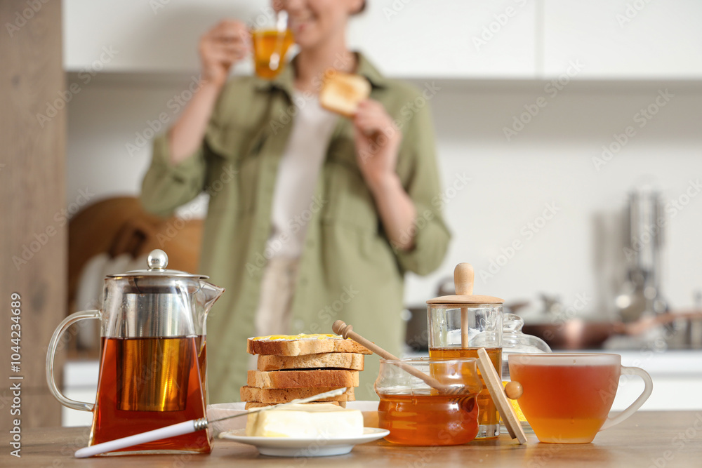 Tasty butter, toasted bread, sweet honey and tea on table in kitchen Tasty butter, toasted bread, sweet honey and tea on table in kitchen