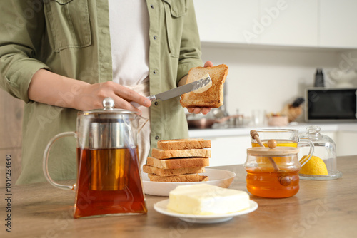 Woman spreading butter onto toasted bread in kitchen