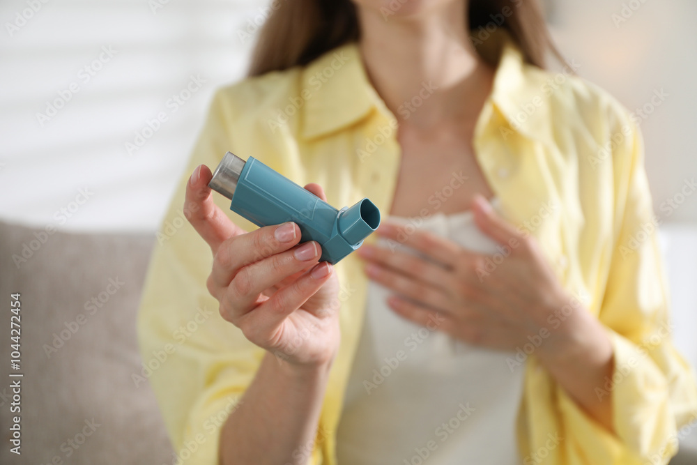 Woman holding asthma inhaler indoors, selective focus Woman holding asthma inhaler indoors, selective focus