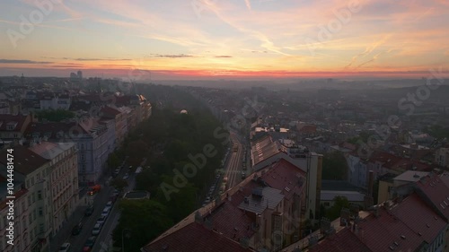 Aerial views capture Prague's urban landscape at sunset, highlighting the lively Vinohradska Street as cars weave through the city, while the sun bathes buildings in a warm glow photo