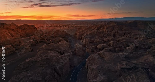 Aerial view of asphalt road and spectacular Yardang landform mountain natural scenery at dusk. The famous Dahaidao uninhabited area natural landscape in Xinjiang, China. photo