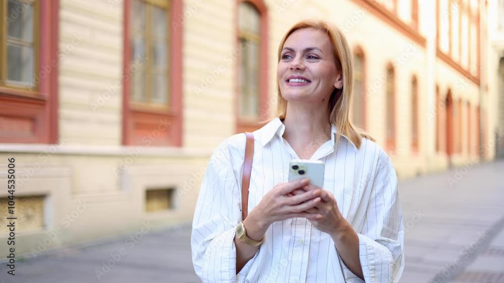 Happy woman surfing the net during her walk Happy woman surfing the net during her walk