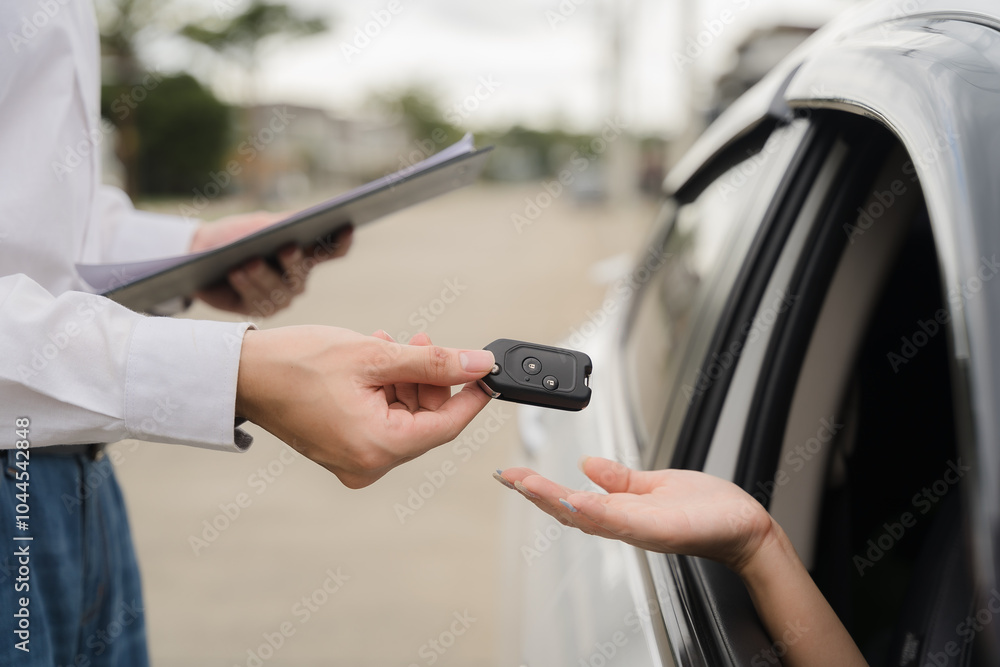Car Key Handover: A close-up shot of a car key being exchanged between a salesperson and a customer, symbolizing a successful car purchase or rental. Car Key Handover: A close-up shot of a car key being exchanged between a salesperson and a customer, symbolizing a successful car purchase or rental.