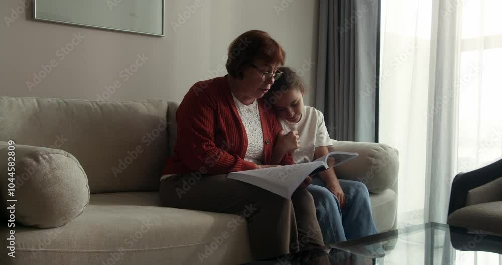 Happy family relationships. Enjoying reading fairy tales together. Adorable little kid girl smiles, expressing happiness spending weekend with her loving grandmother at home. Slow motion in 4K Happy family relationships. Enjoying reading fairy tales together. Adorable little kid girl smiles, expressing happiness spending weekend with her loving grandmother at home. Slow motion in 4K