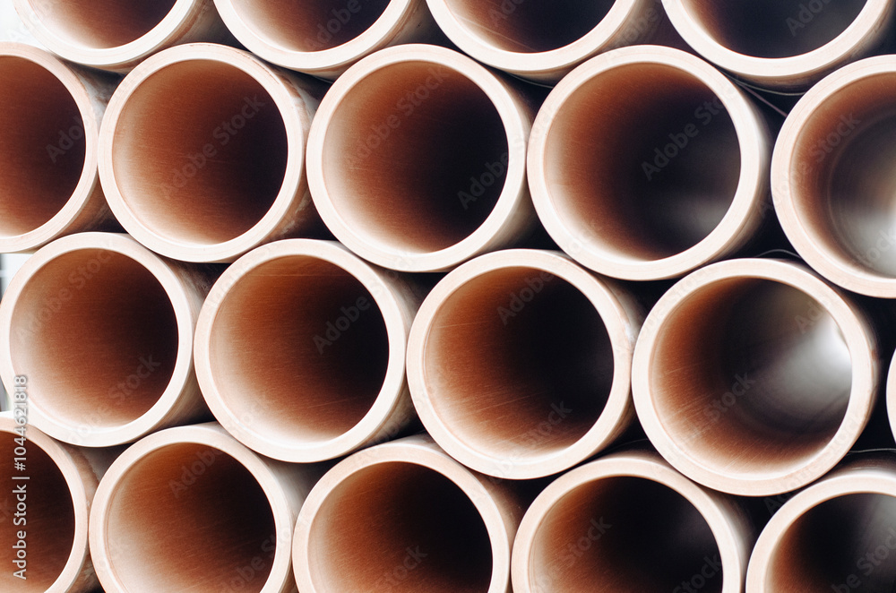 Stacks of ceramic clay drainage pipes arranged neatly in a warehouse showcasing industrial materials in natural light Stacks of ceramic clay drainage pipes arranged neatly in a warehouse showcasing industrial materials in natural light