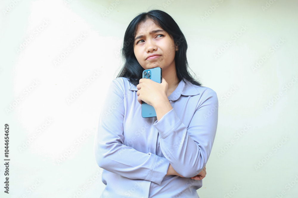 portrait of confused asian woman holding cell phone with folded arm looking away isolated in white, pensive expression of female employee portrait of confused asian woman holding cell phone with folded arm looking away isolated in white, pensive expression of female employee