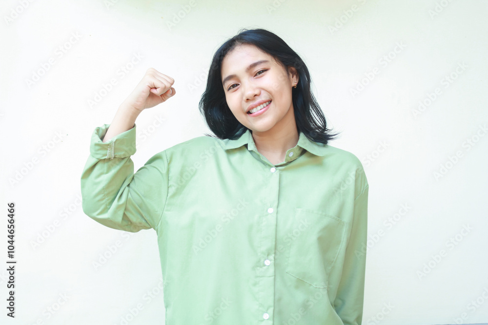 proud asian woman wearing green casual oversized shirt raising arms show strong bicep looking at camera with confident smile standing over isolated background proud asian woman wearing green casual oversized shirt raising arms show strong bicep looking at camera with confident smile standing over isolated background