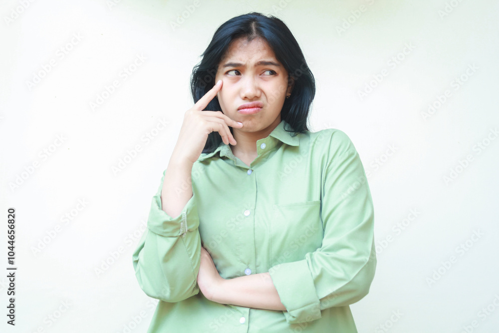 thoughtful asian woman with dark hair looking away curious with folding arms and touching her cheek wearing green oversized shirt, annoyed female feeling afraid and scared isolated on white thoughtful asian woman with dark hair looking away curious with folding arms and touching her cheek wearing green oversized shirt, annoyed female feeling afraid and scared isolated on white
