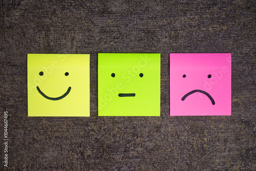 colorful sticky notes with emotion faces expression like smile, flat and sad mood on cement background photo