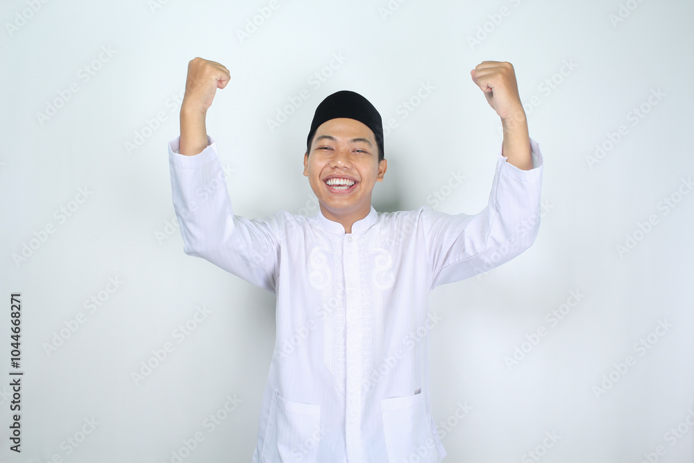 happy muslim asian man raising fist show victory gesture in eid mubarak celebration isolated on white background happy muslim asian man raising fist show victory gesture in eid mubarak celebration isolated on white background