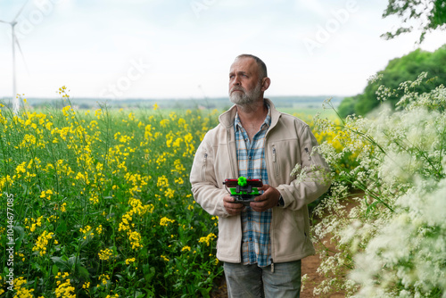 A thoughtful farmer operates a drone among vibrant wildflowers in a picturesque rural landscape at dusk