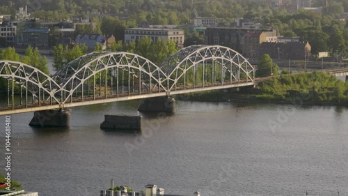 Cinematic pan following beautiful flying birds over river with bridge at sunset photo