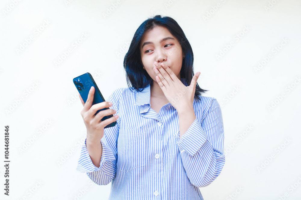 happy asian woman using mobile phone covering her mouth with surprised expression wearing striped shirt isolated on white background happy asian woman using mobile phone covering her mouth with surprised expression wearing striped shirt isolated on white background