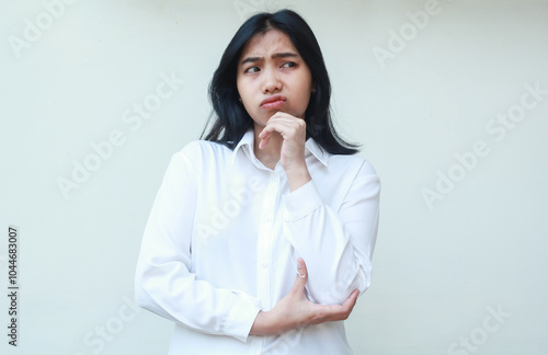 image of thoughtful asian young business woman manager wear formal white shirt with hands on chin and arms folded looking aside contemplating, standing curios female