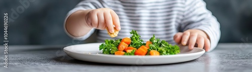 Child's hand reaching for colorful carrots on a plate with greens.